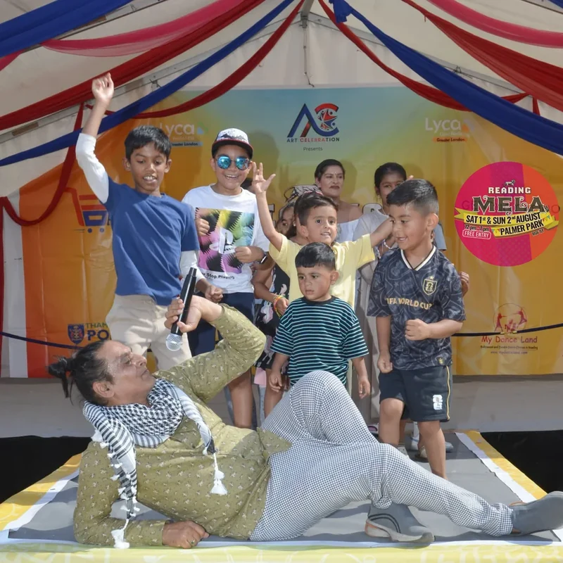 Ritesh sharing a lively moment with children on stage at a Reading community event.